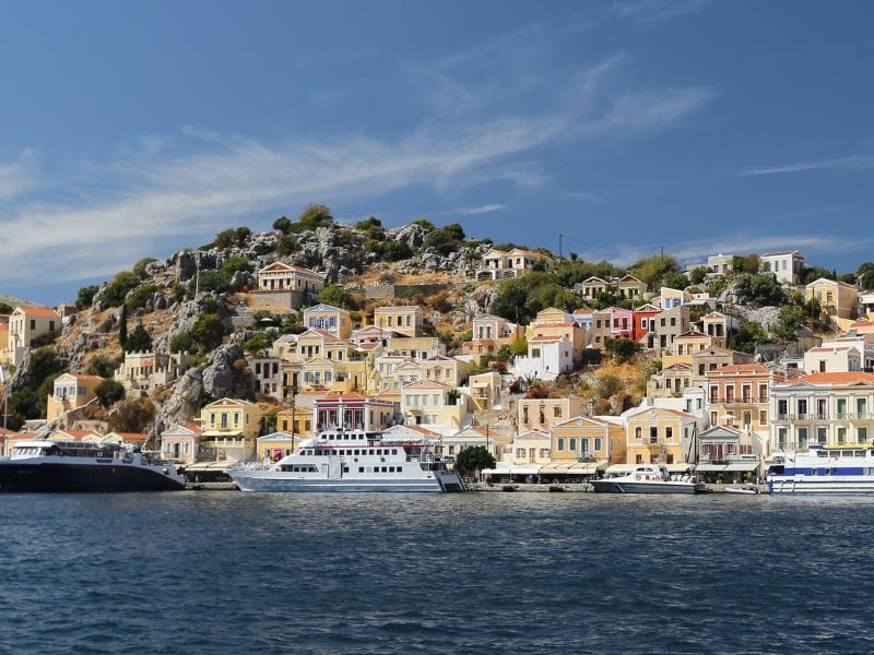 Neoclassical harbor and colorful hillside houses featured in Symi island tours.